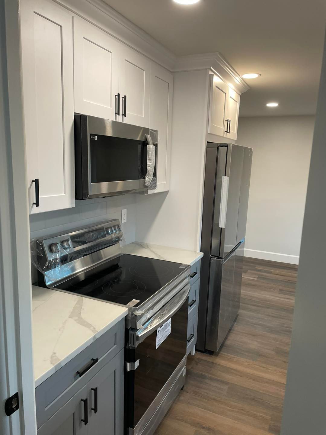 A kitchen with a stove , microwave , refrigerator and sink.