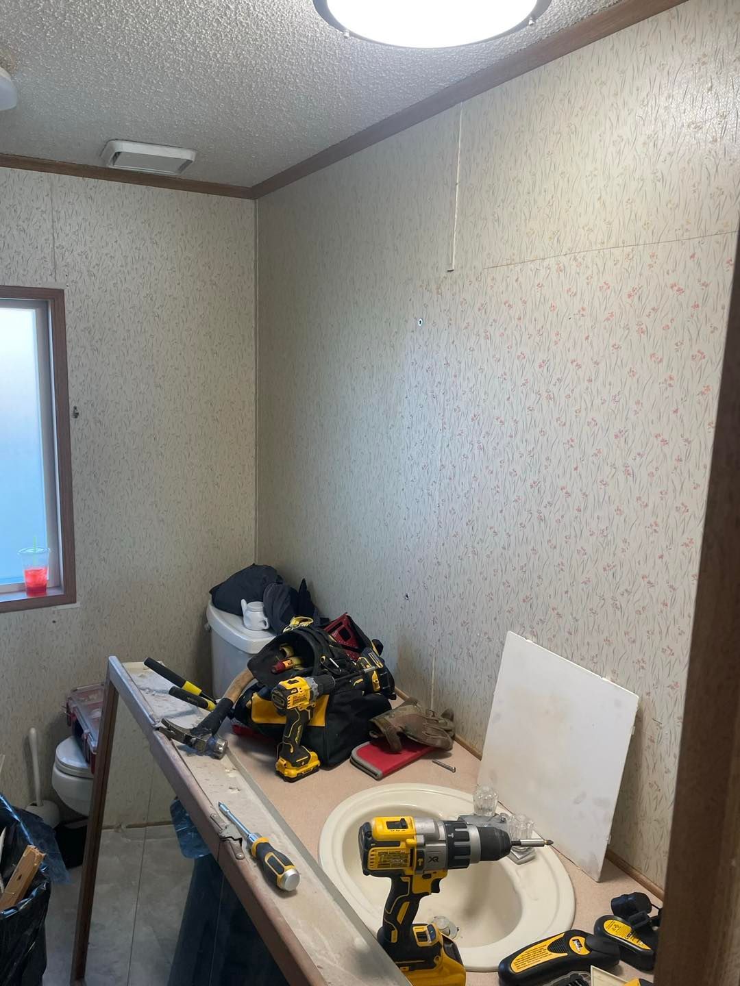 A bathroom with a sink and a drill on the counter.