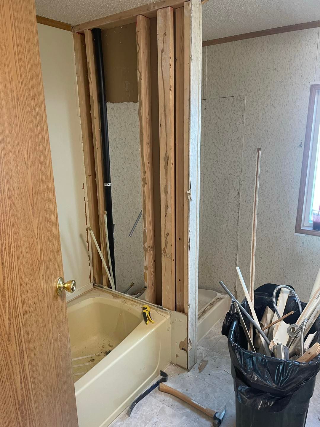 A bathroom under construction with a bathtub and a trash can.