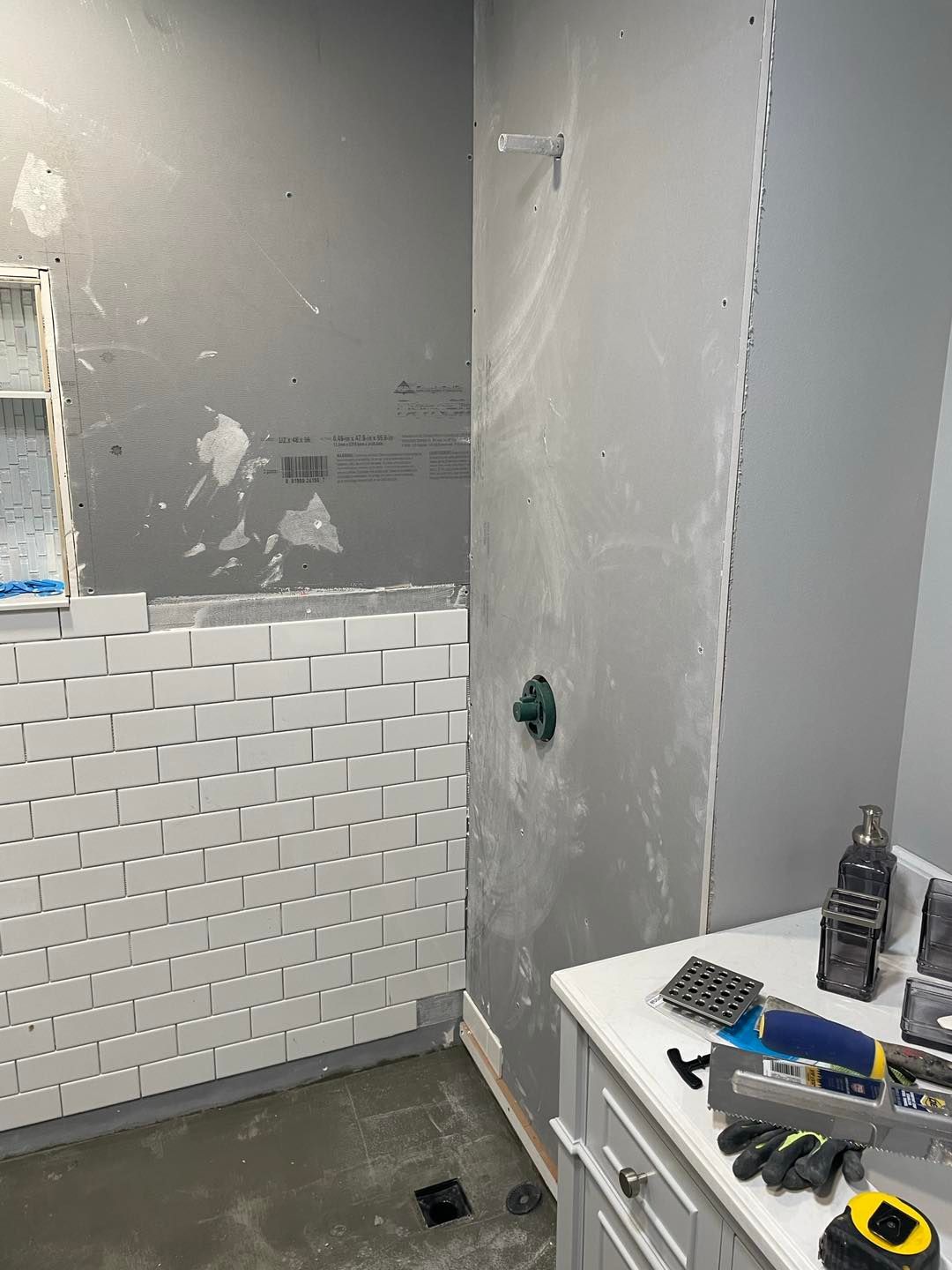 A bathroom under construction with white tiles and a sink.