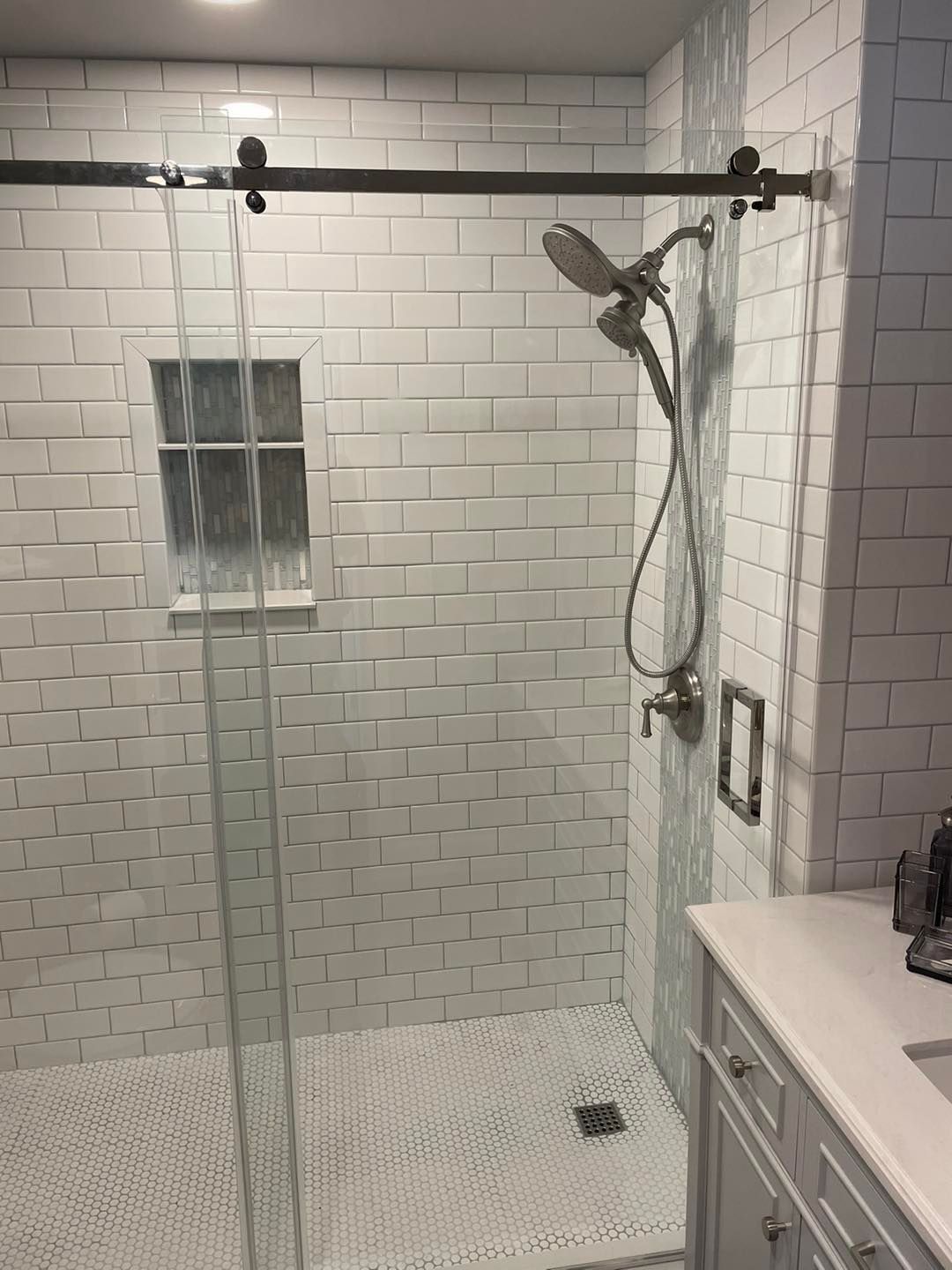 A bathroom with a walk in shower with a sliding glass door.