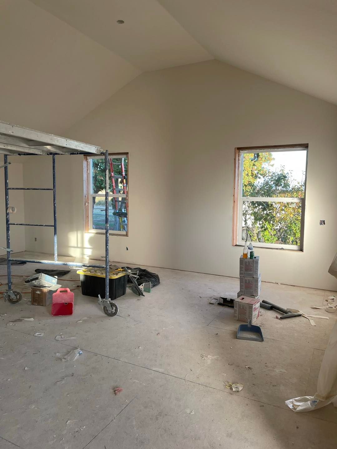 An empty room with a vaulted ceiling and two windows.