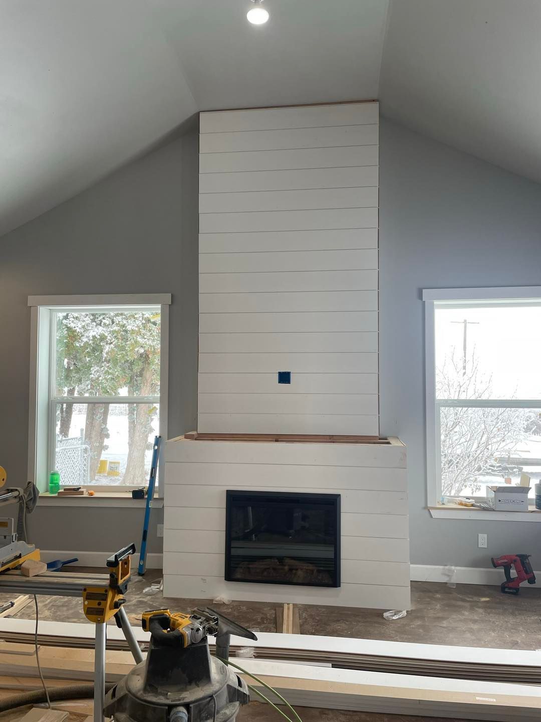 A fireplace is being built in a living room with a vaulted ceiling.