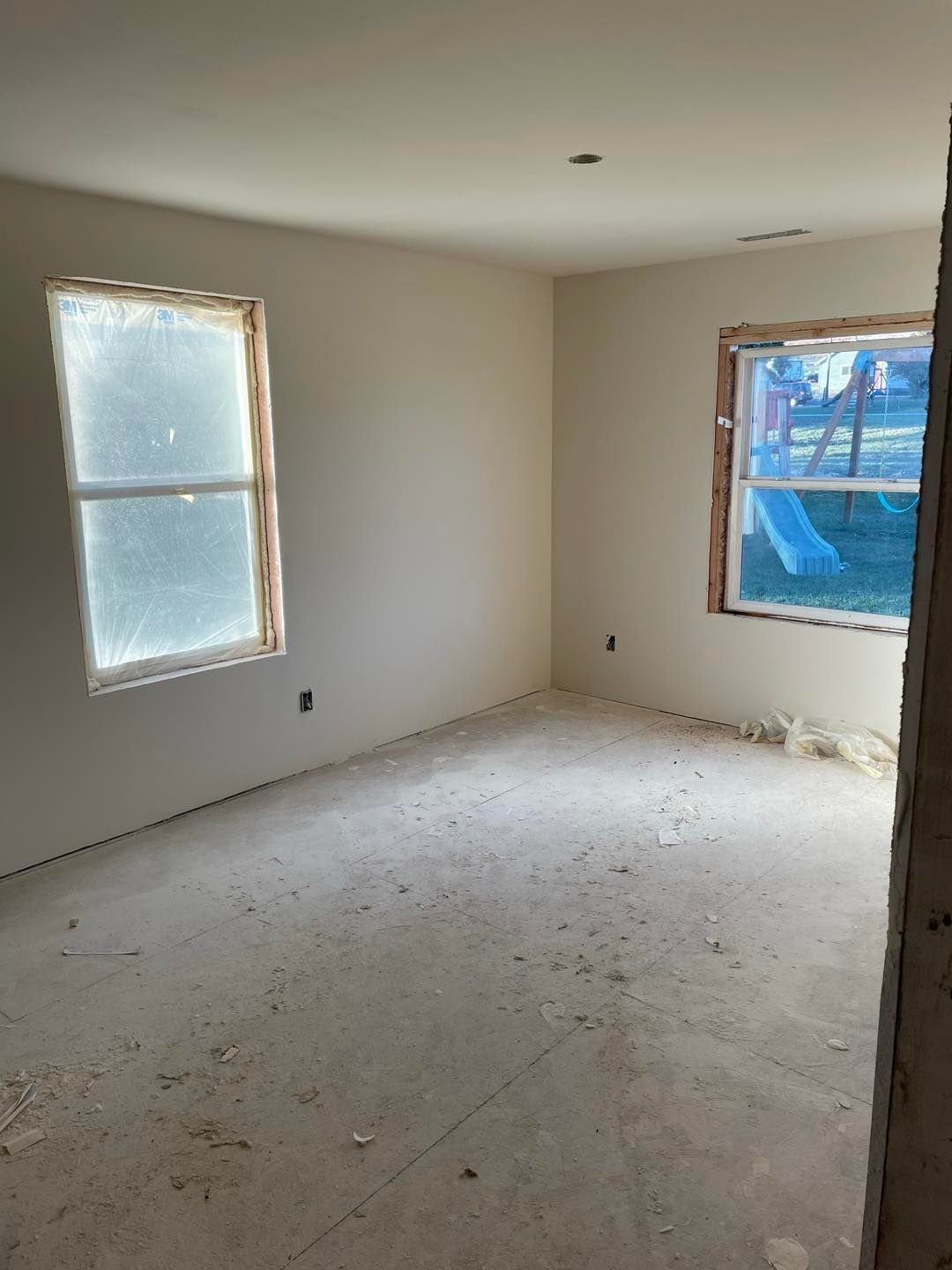 An empty room with two windows in a house under construction.