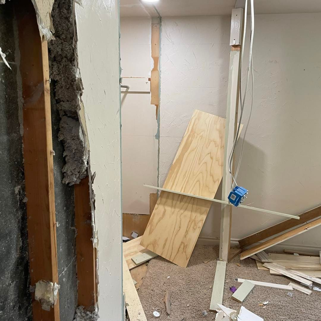 A room with a broken wall and a wooden plank on the floor.