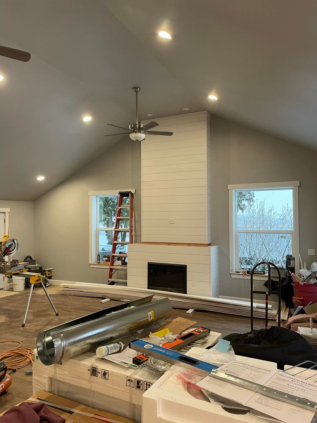 A living room with a fireplace and a ceiling fan.