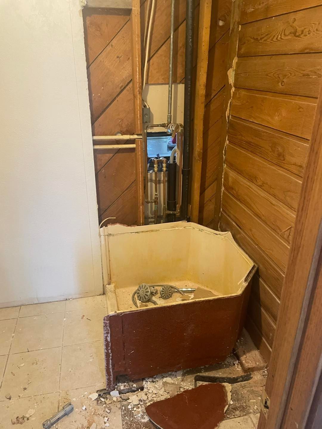 A bathroom with a bathtub in it and a wooden wall.