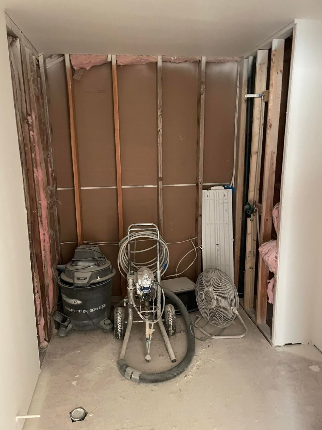 A room with a vacuum cleaner and a fan in it.