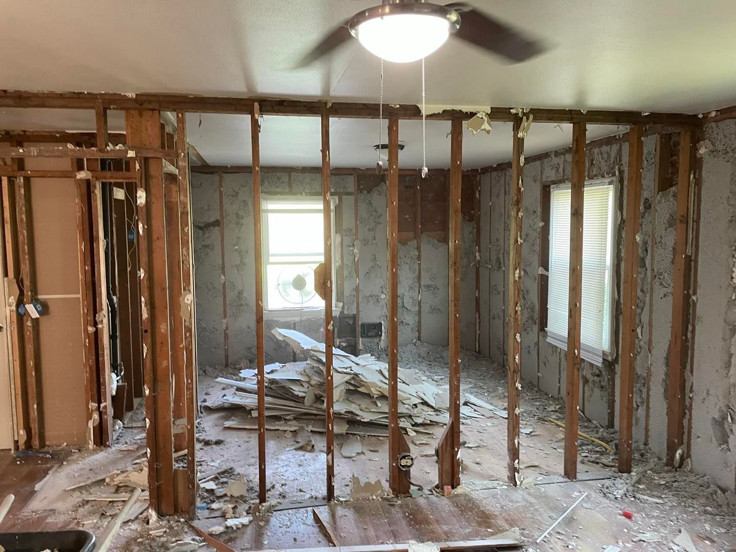 A living room in a house that is being remodeled with a ceiling fan.