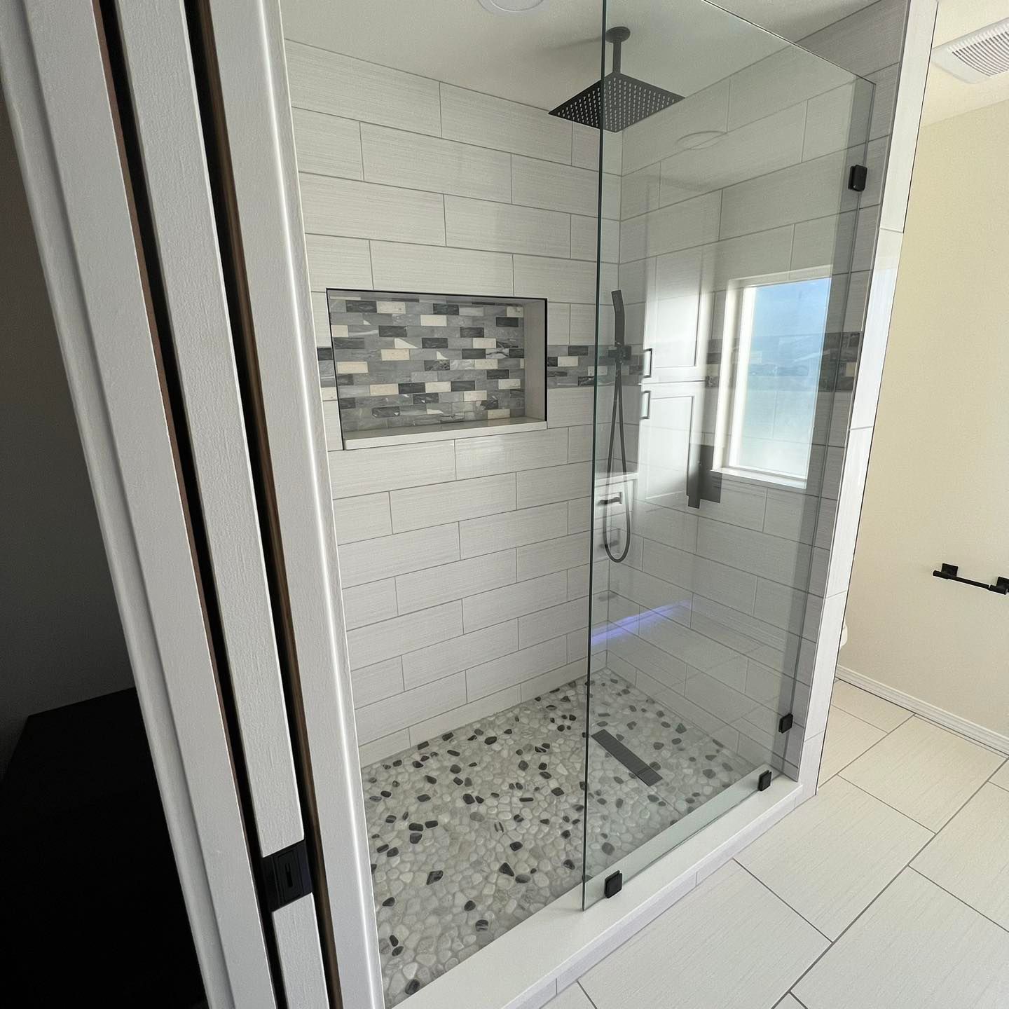 A bathroom with a walk in shower and a window