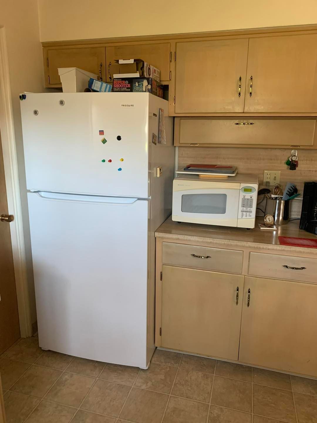 A kitchen with a refrigerator , microwave , and cabinets.