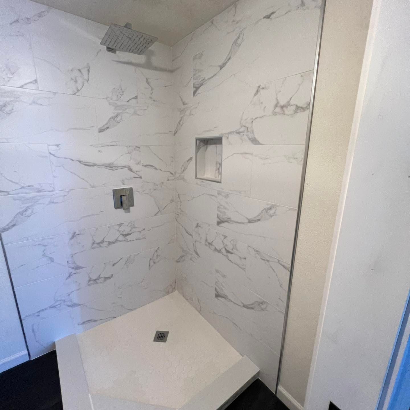 A bathroom with marble walls and a walk in shower