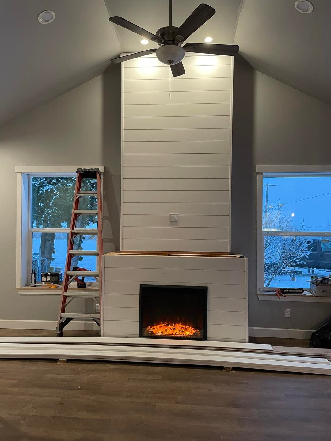 A living room with a fireplace and a ceiling fan.