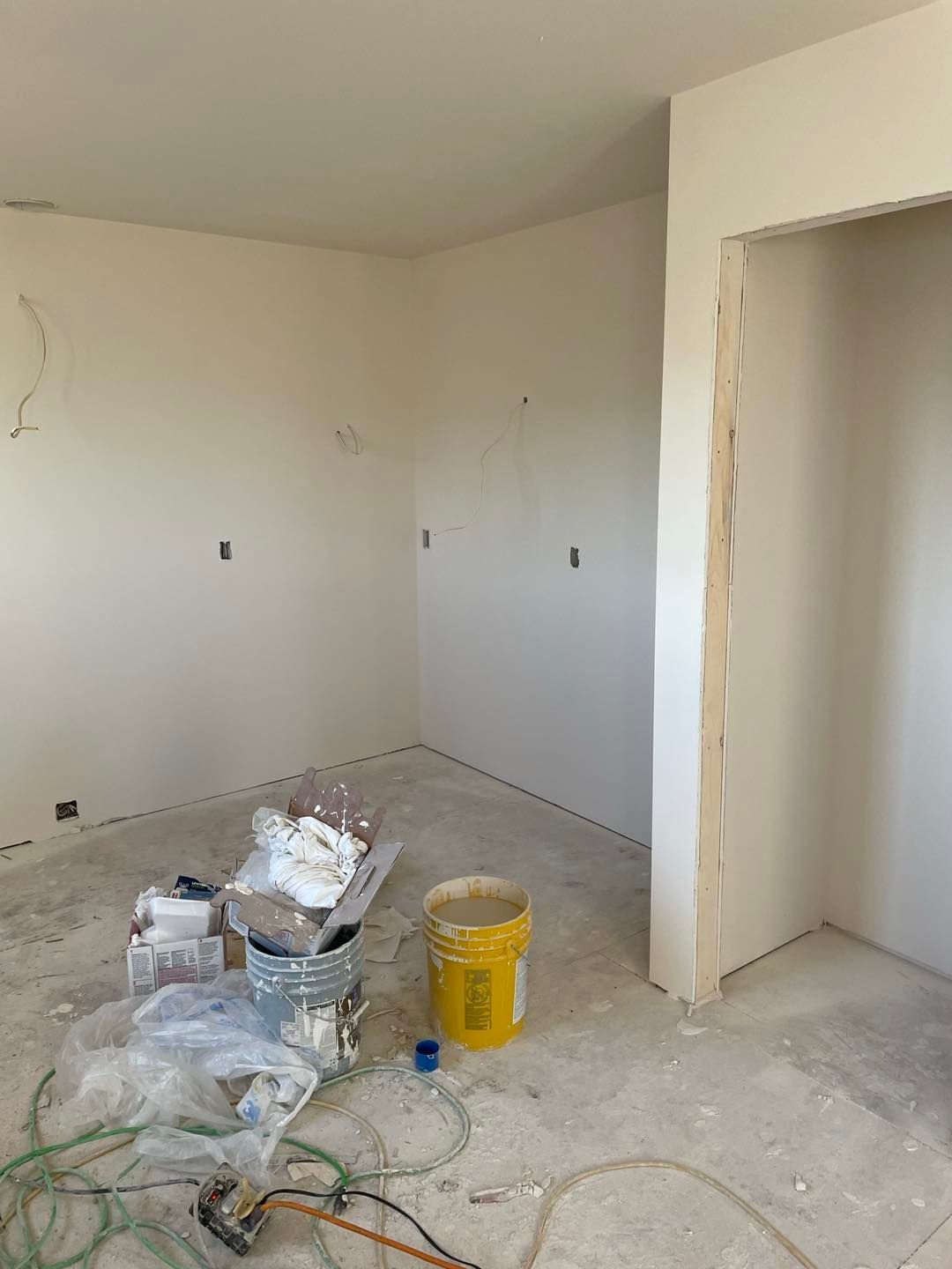 A room with white walls and a yellow bucket on the floor.