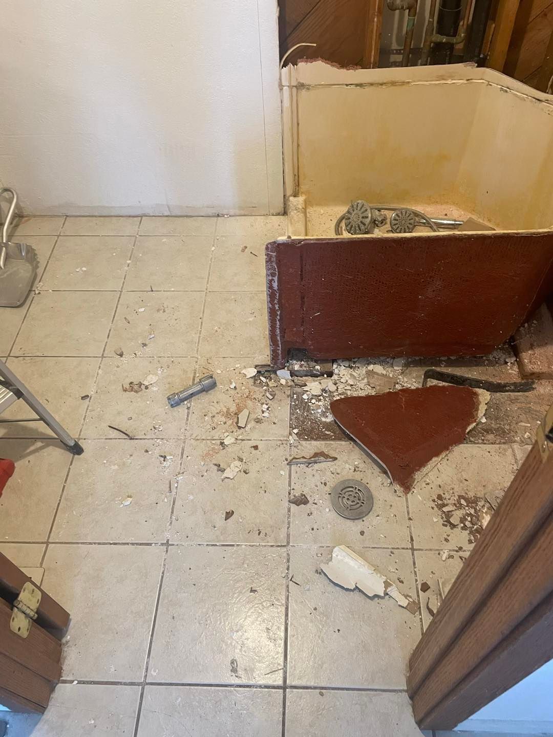 A bathroom with a bathtub being removed and a broken tile floor.