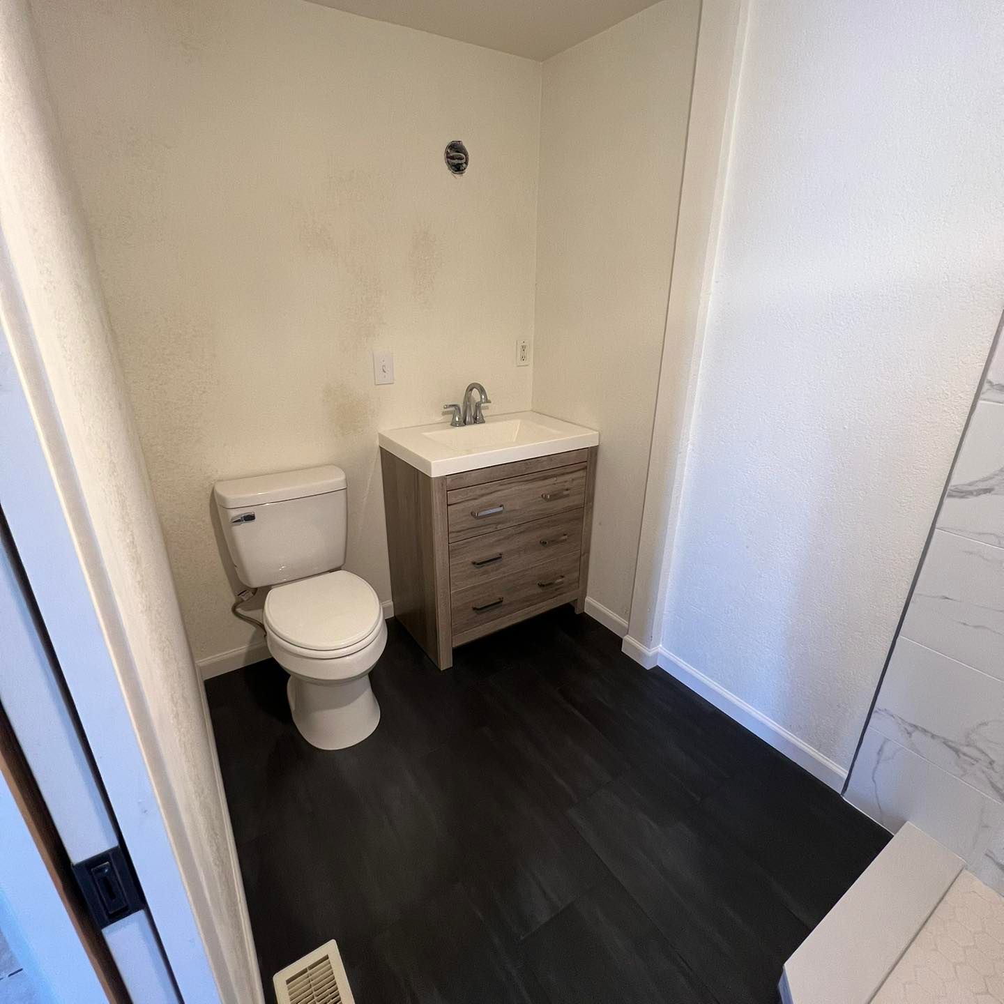 A bathroom with a toilet , sink and dresser.