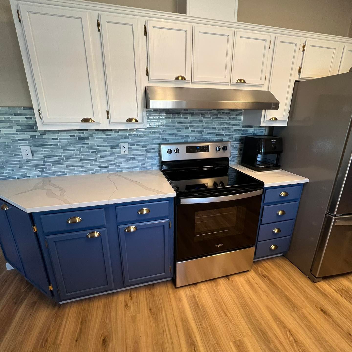 A kitchen with blue cabinets , a stove , and a refrigerator.