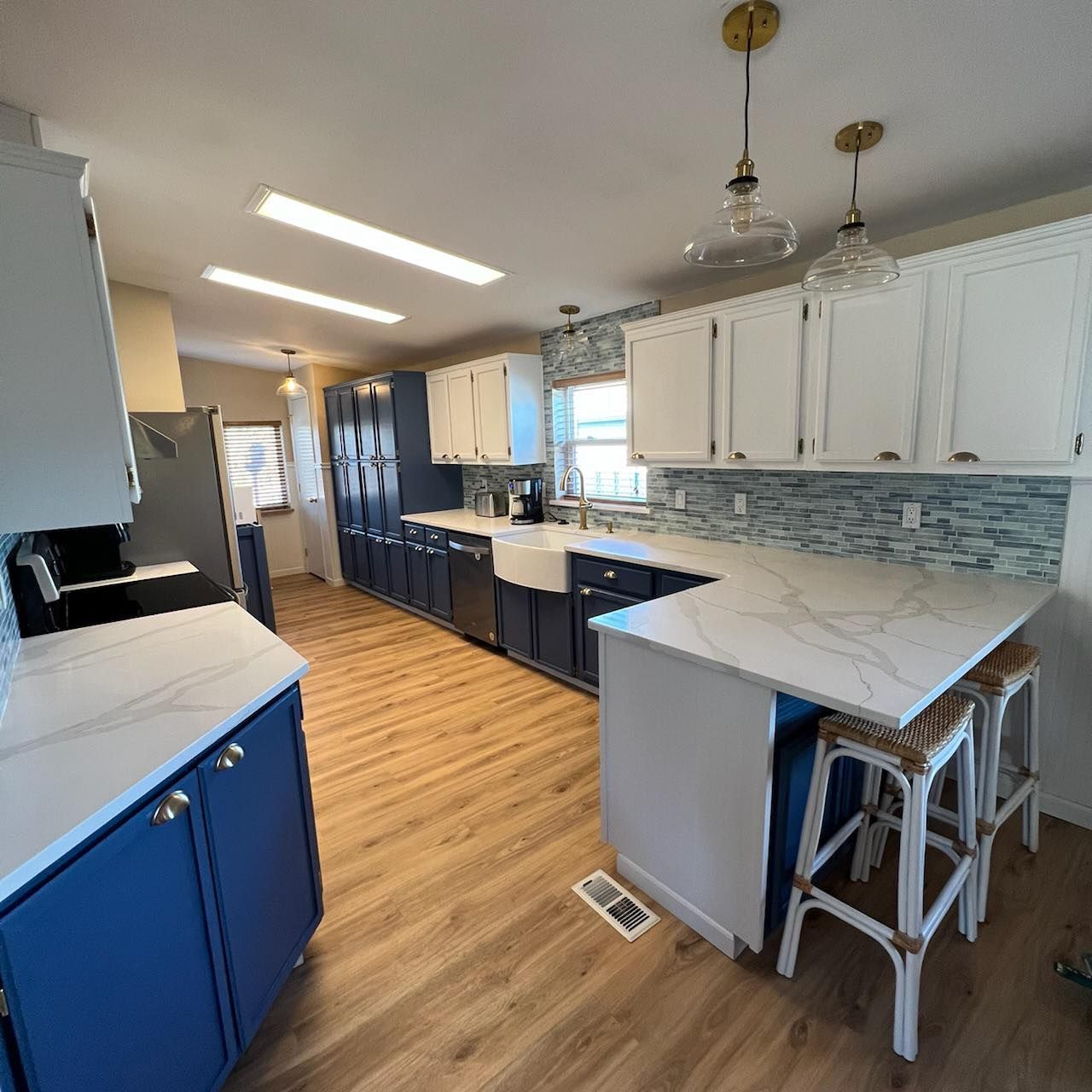 A kitchen with blue cabinets and white counter tops.