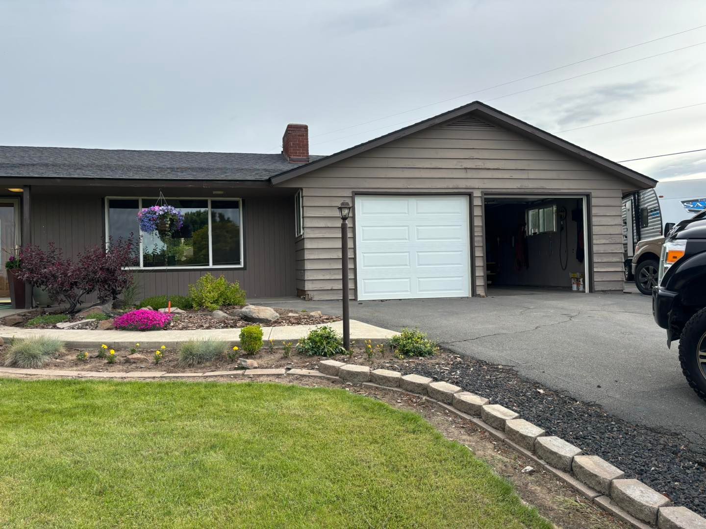 A car is parked in front of a house with a garage door open.