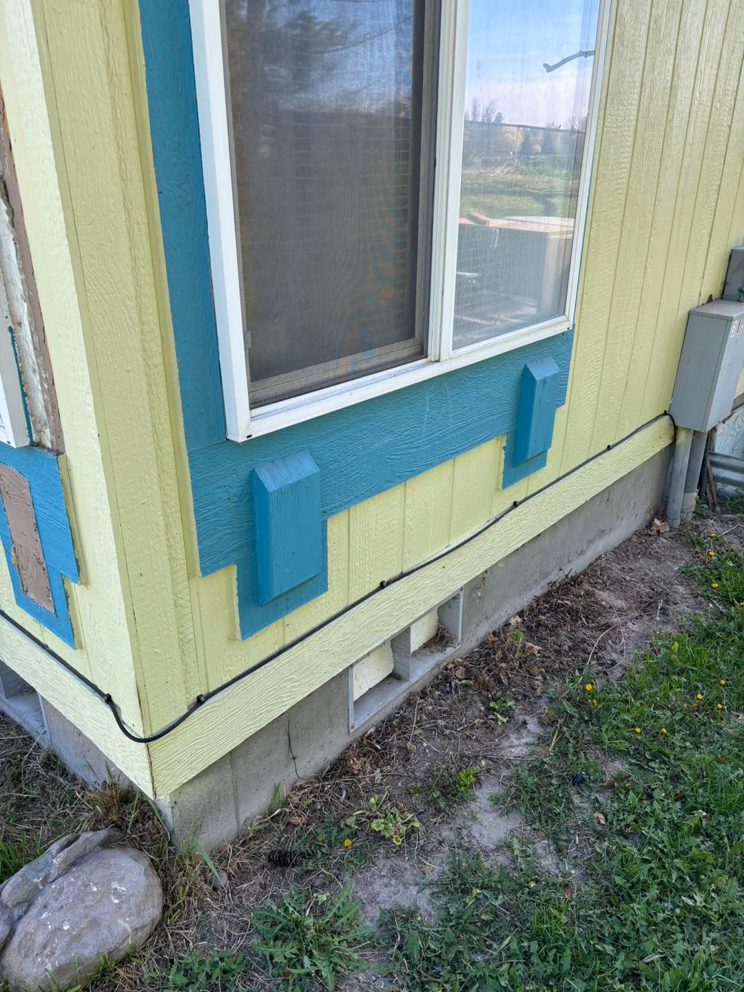 A yellow and blue house with a window on the side.