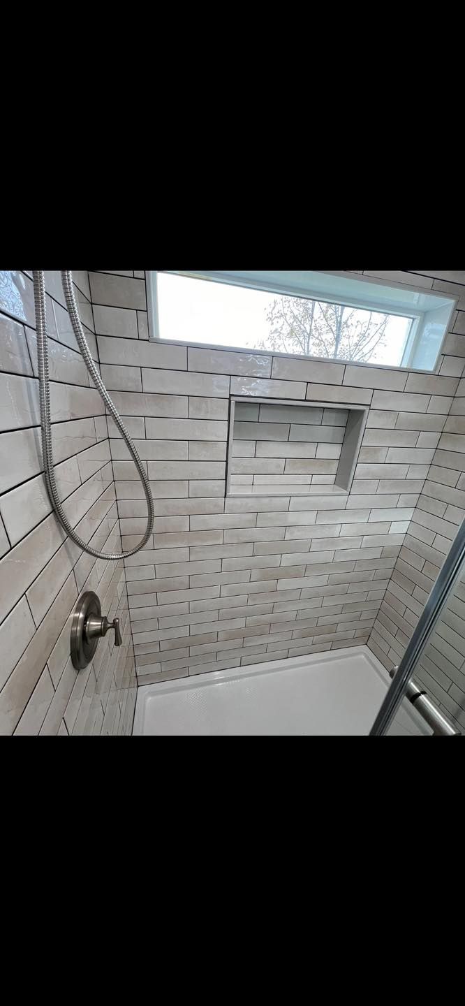 A bathroom with a tub , shower , and window.
