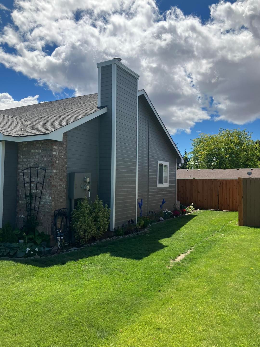 A house with a large lawn in front of it and a wooden fence.