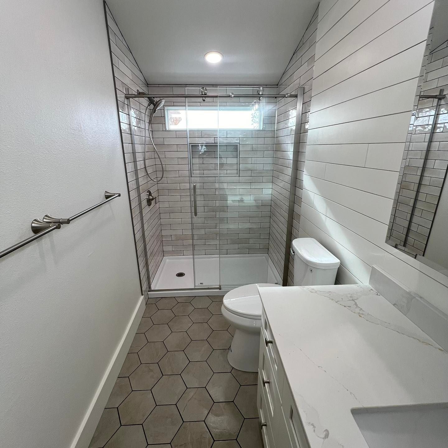 A bathroom with a toilet , sink , shower and mirror.