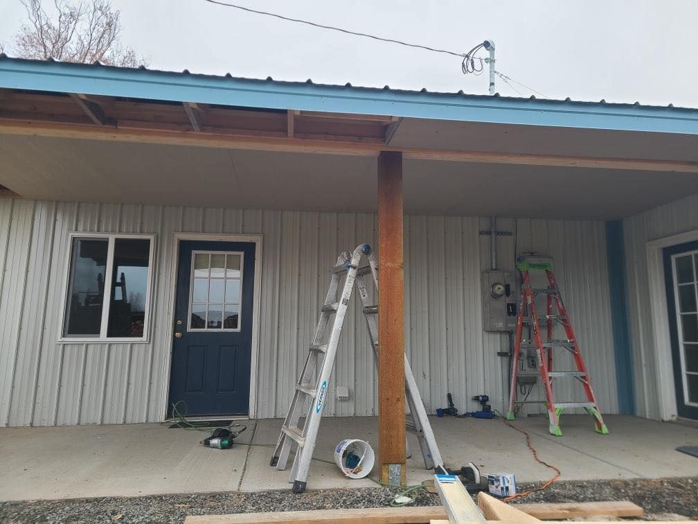 A white house with a blue door and a ladder on the porch.