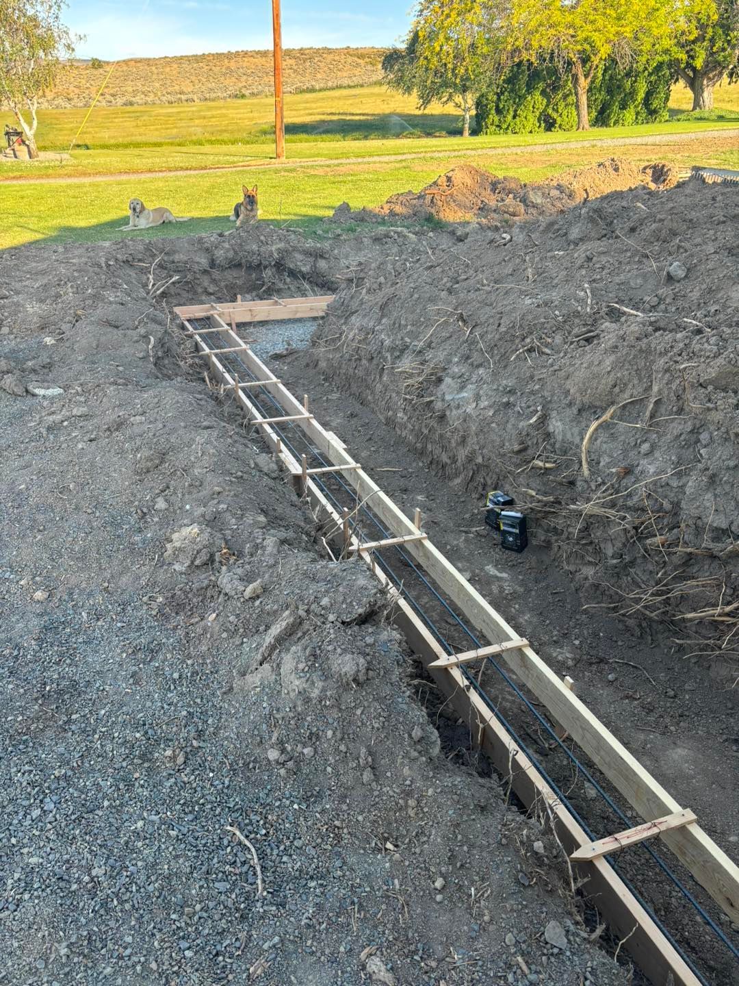 A concrete foundation is being built in a dirt field.