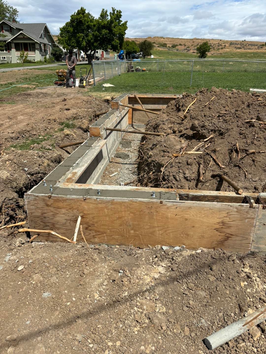 A concrete foundation is being built in a dirt field.
