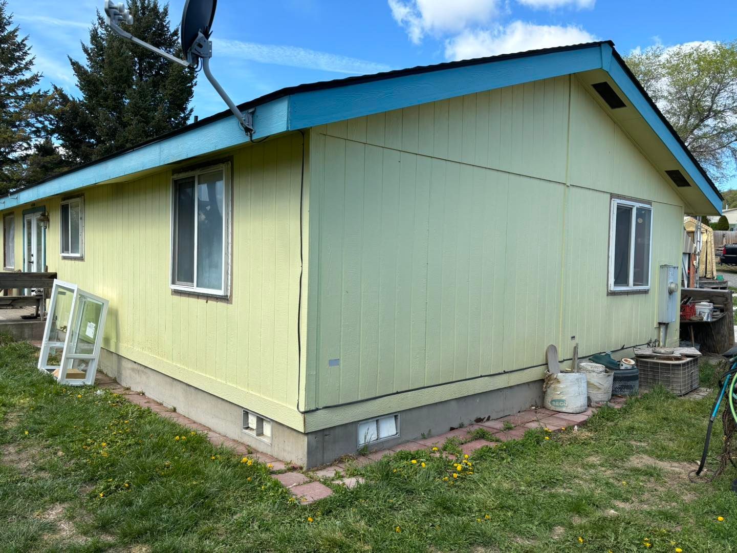A yellow house with a blue roof is sitting in the grass.