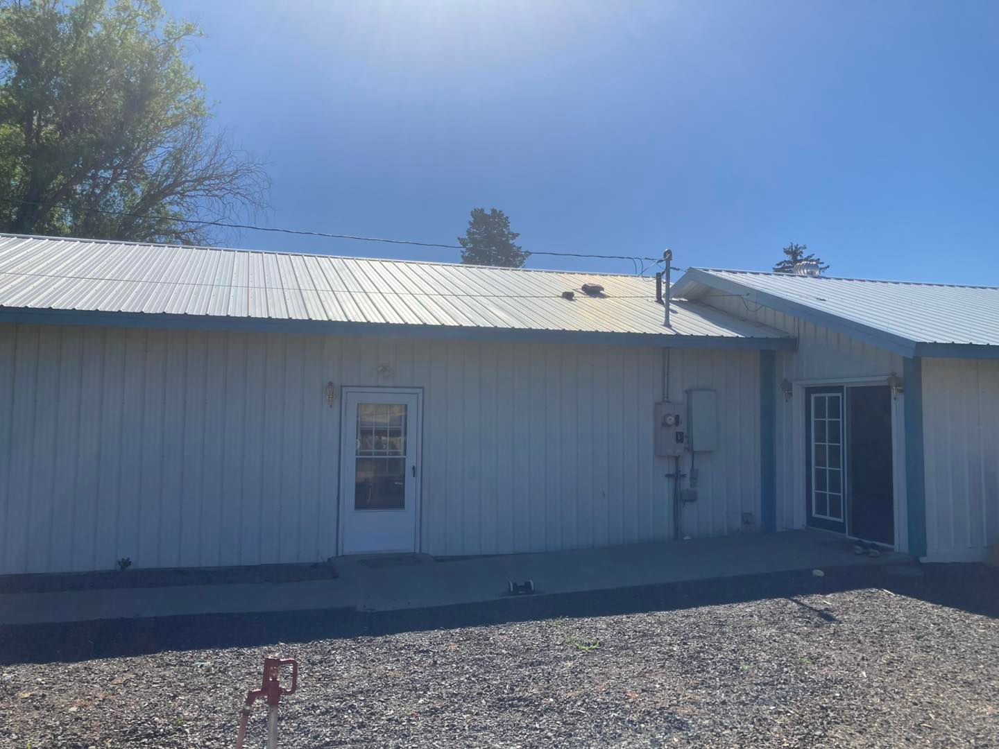 A white house with a metal roof and a door.