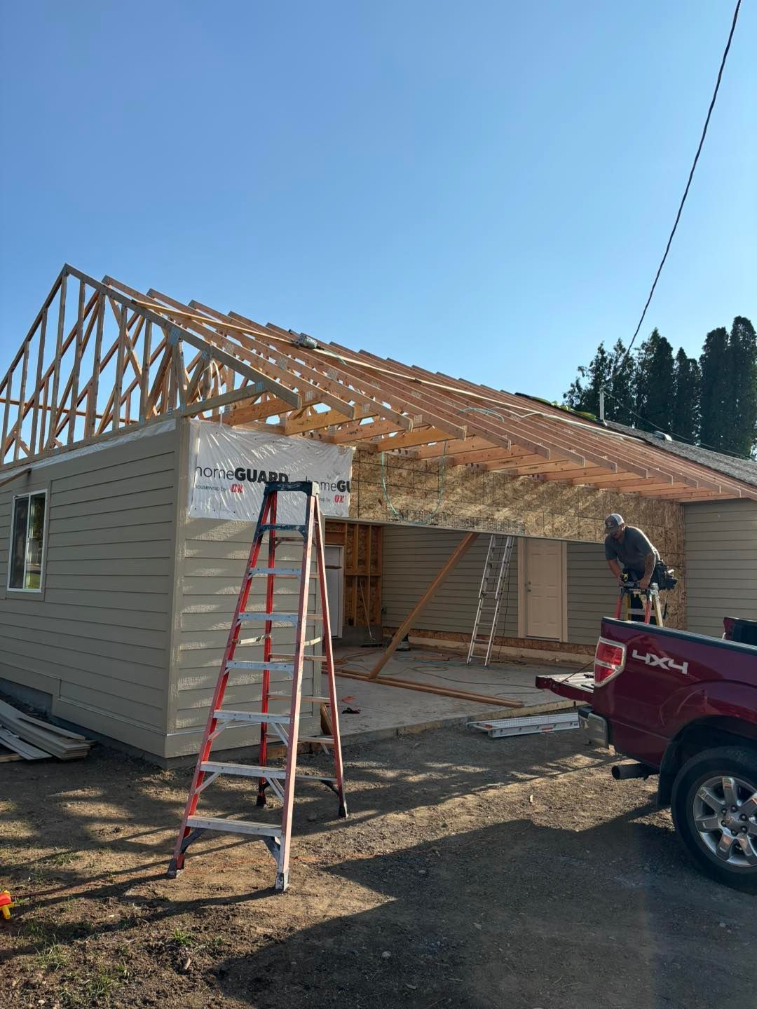 A red truck is parked in front of a house under construction.