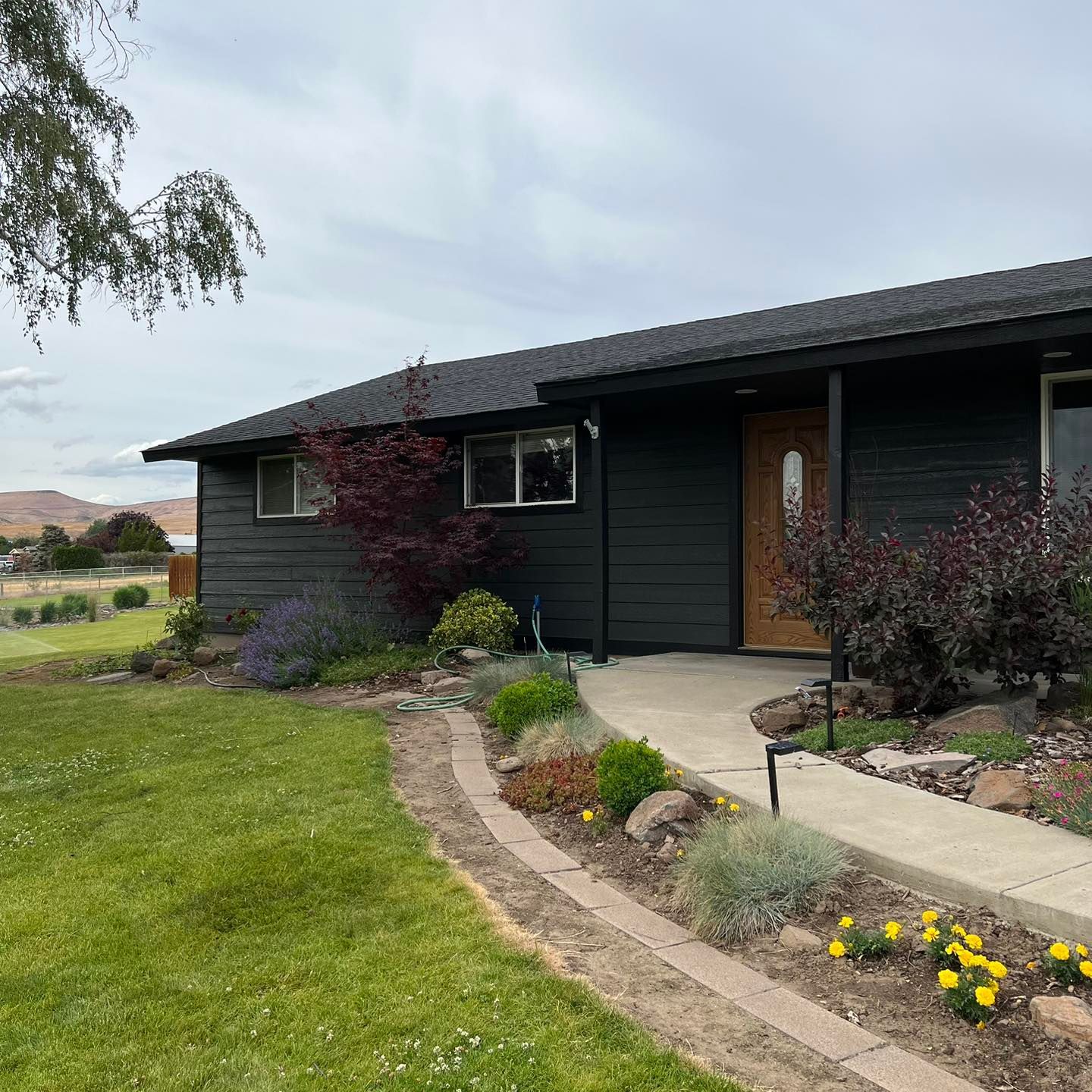 A black house with a concrete walkway leading to it