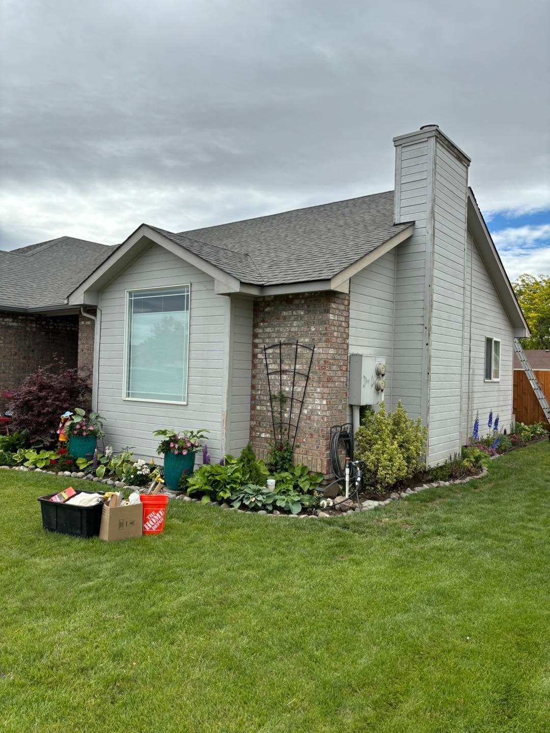 A white house with a gray roof is sitting on top of a lush green lawn.