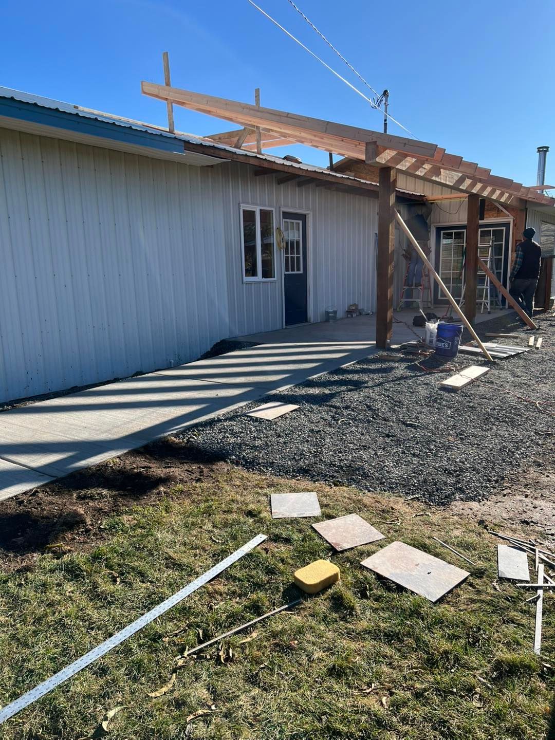 A man is sitting on the ground in front of a building under construction.