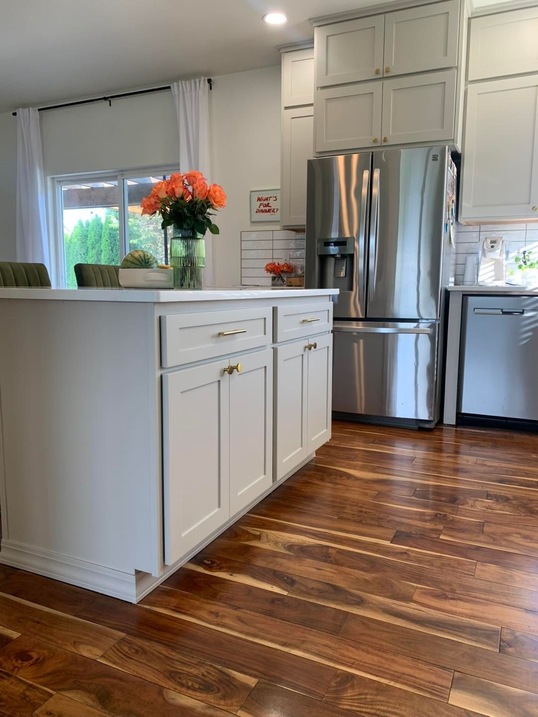 A kitchen with white cabinets , stainless steel appliances , and hardwood floors.