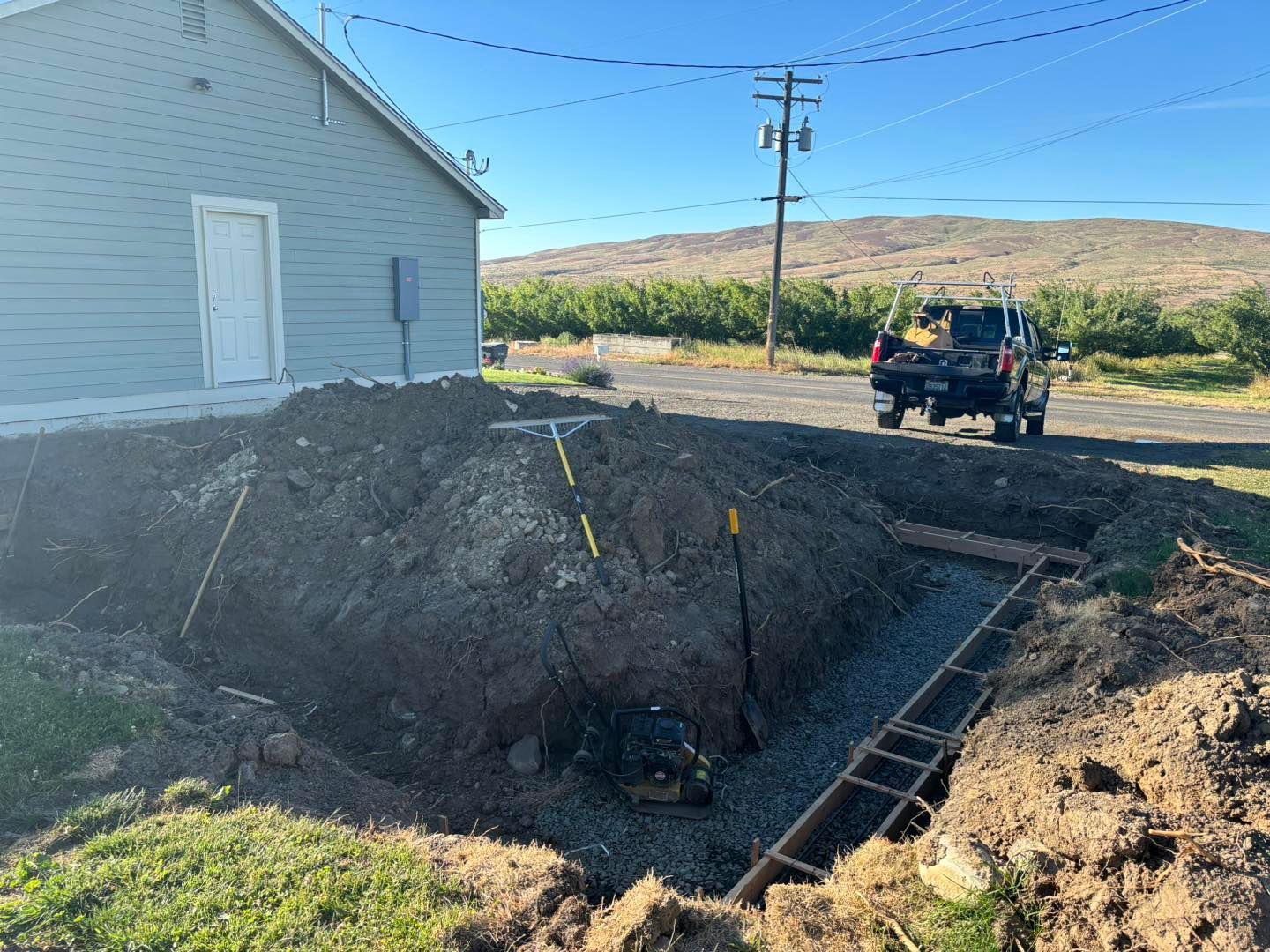 A truck is parked in front of a house next to a large hole in the ground.