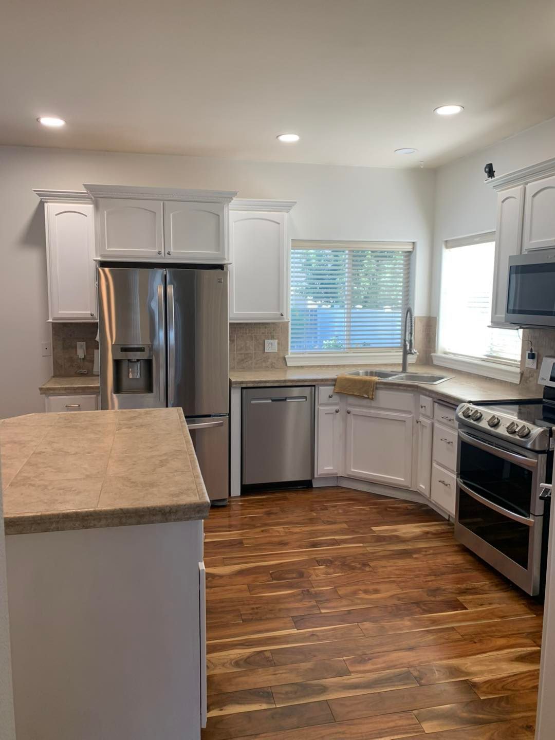 A kitchen with white cabinets , stainless steel appliances , and hardwood floors.