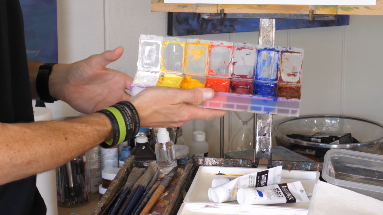 man holding a messy paint box