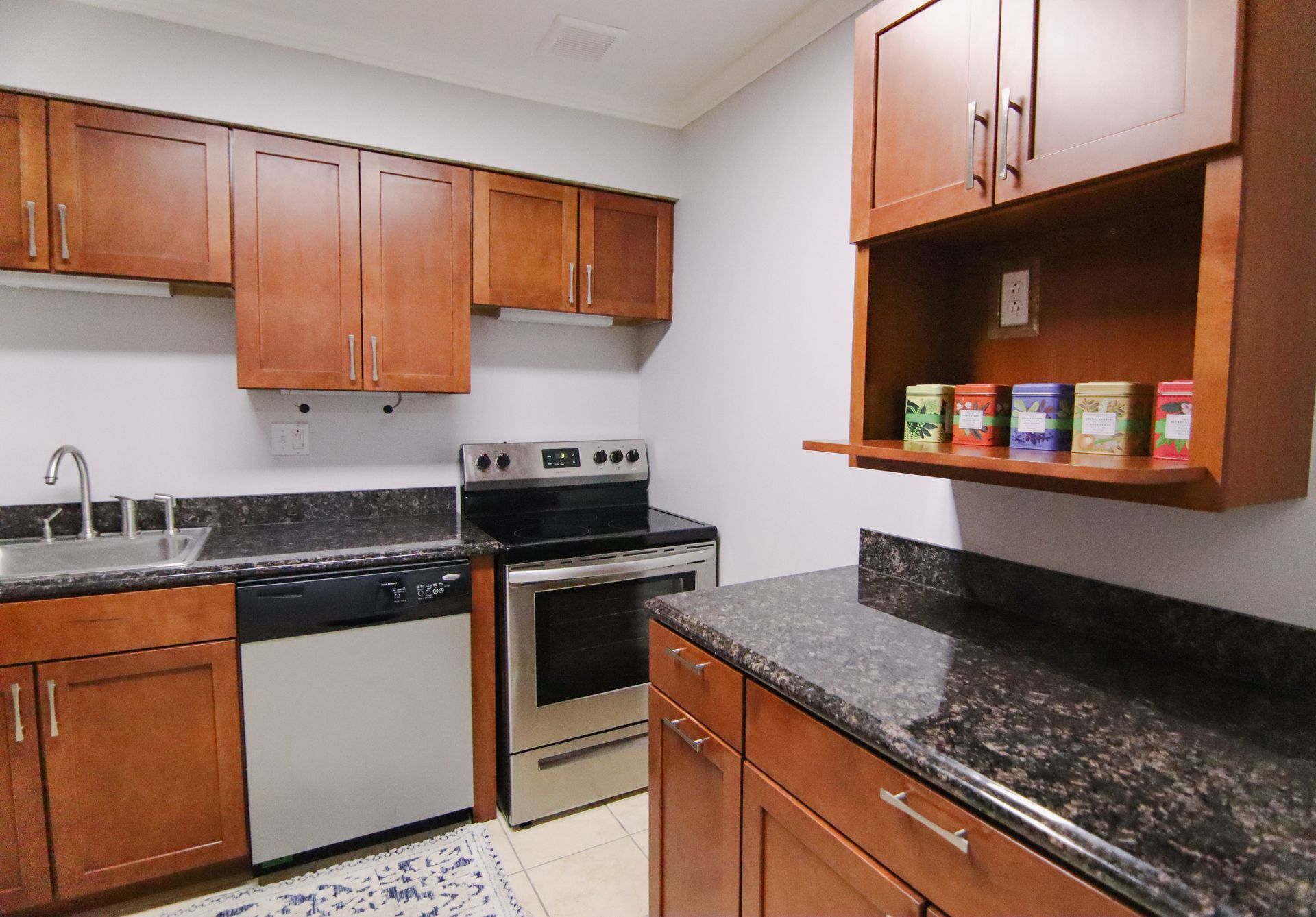 Kitchen with dark granite countertops, stainless steel appliances, and brown cabinets.