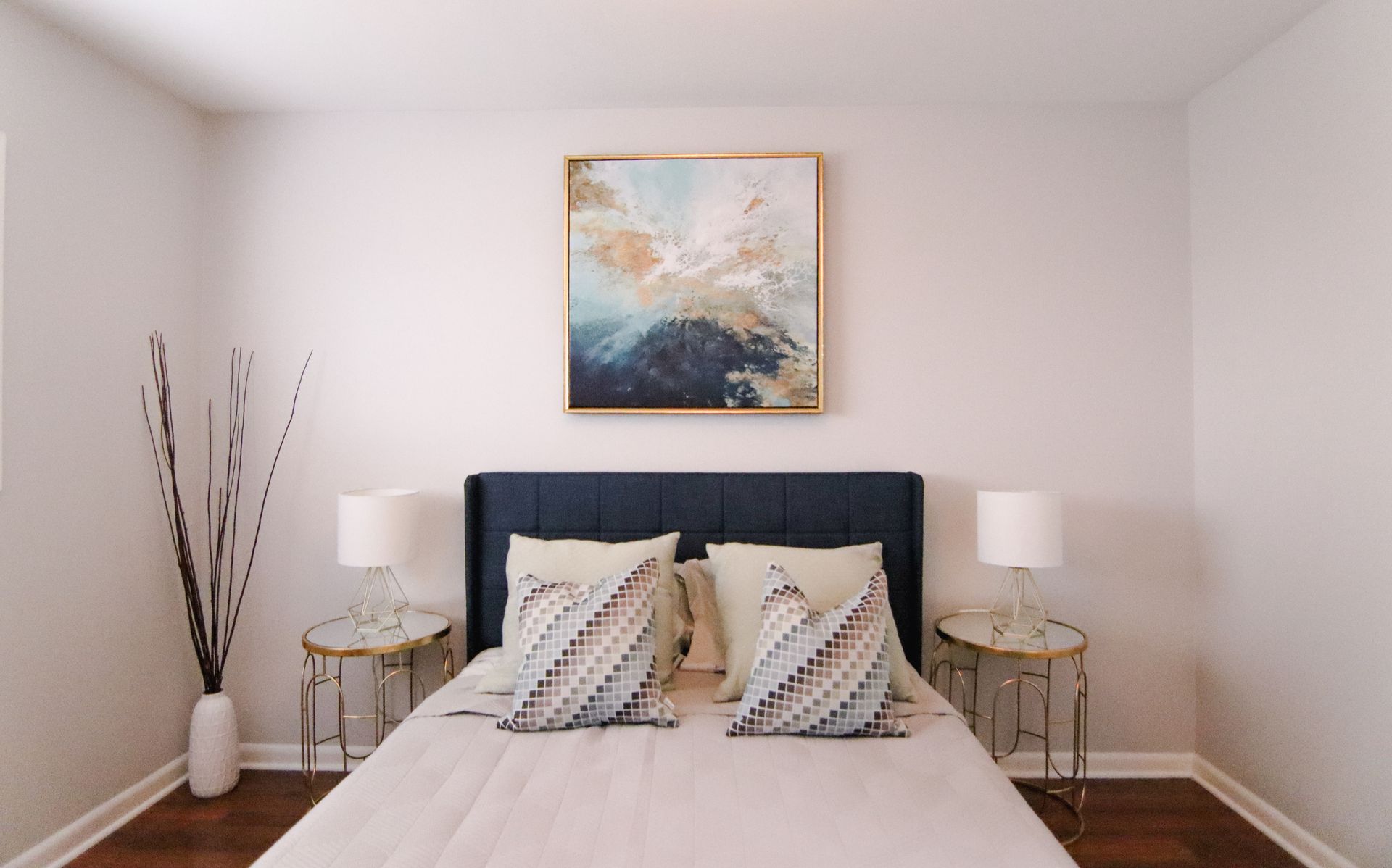 Bedroom with bed, nightstands, artwork, and white walls.