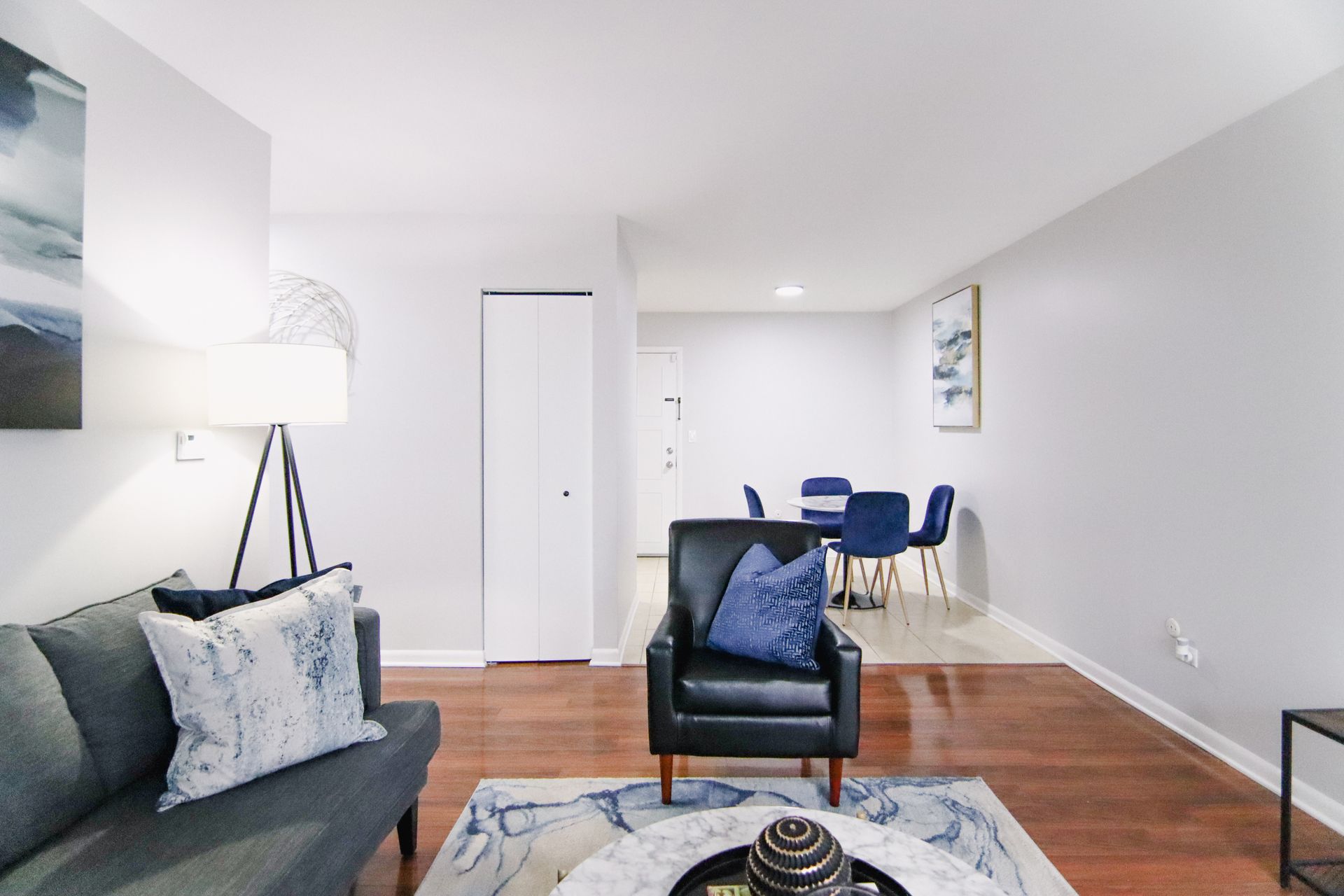 Living room with a couch, armchair, dining table, and hardwood floors.