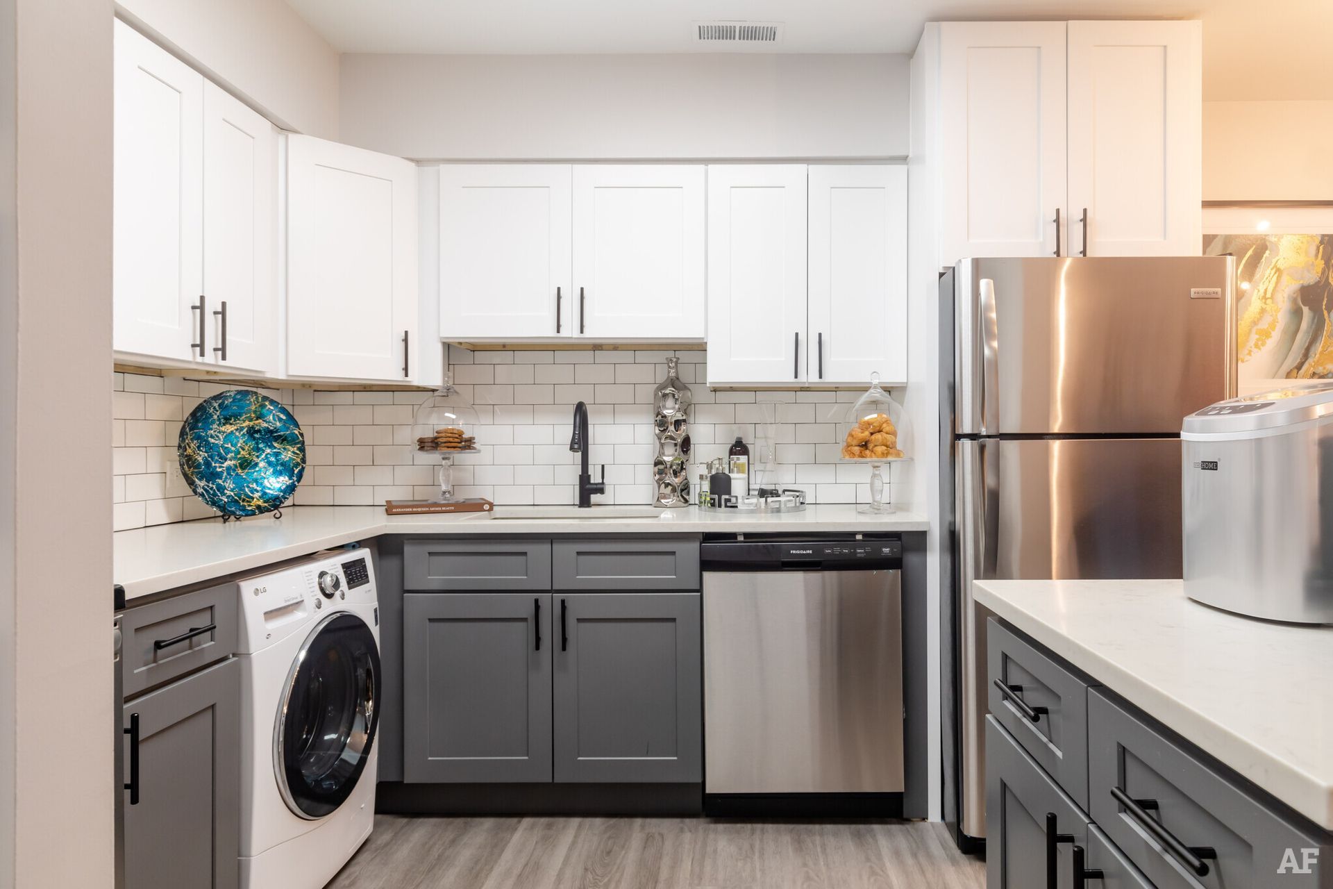 Modern kitchen with white and gray cabinets, stainless steel appliances, and a washing machine.