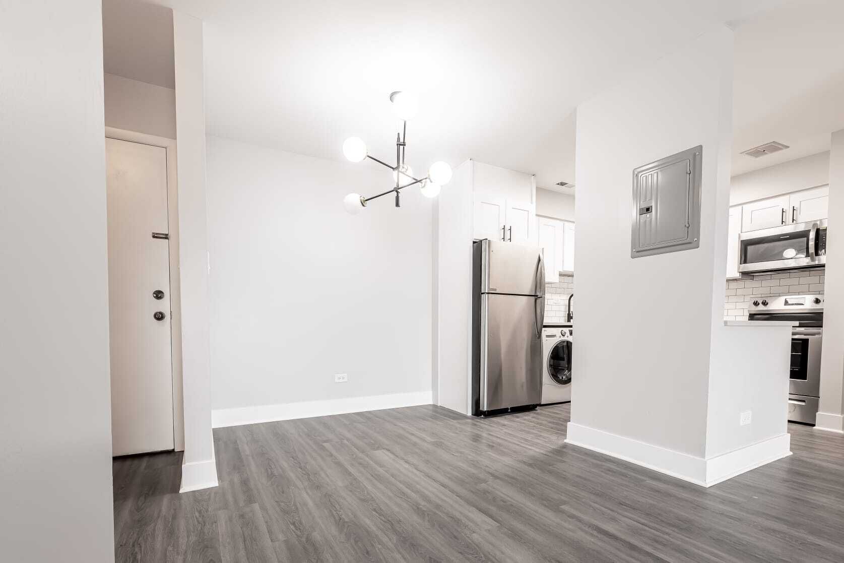 Empty apartment interior with gray flooring, white walls, and stainless steel appliances.
