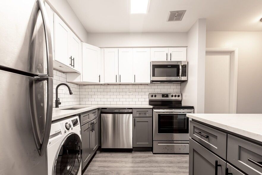Modern kitchen with white cabinets, stainless steel appliances, and gray accents.