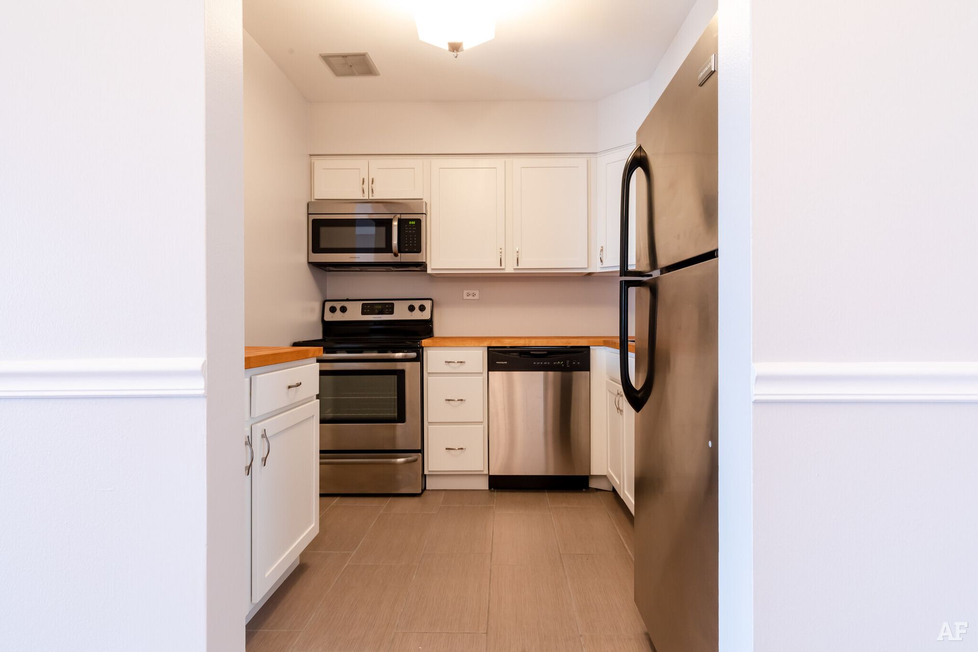 Kitchen with white cabinets, stainless steel appliances, and a wooden countertop.