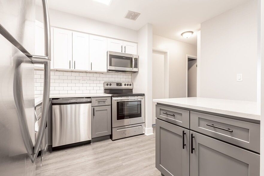 Modern kitchen with stainless steel appliances, white cabinets, and gray island.