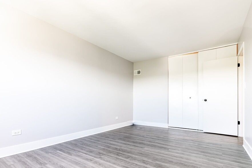 Empty room with gray wood-look floor, white walls, and closet doors.