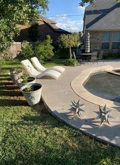 A patio with chairs and a swimming pool in the backyard of a house.